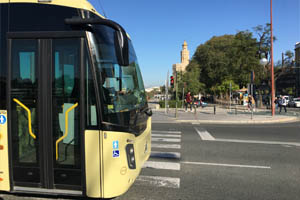 Un autobus interurbano con publicidad junto a la Torre del Oro en Sevilla